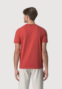 T-shirt rossa a maniche corte in morbido cotone, con collo tondo e un piccolo dettaglio decorativo sul retro. Taglio semplice e rilassato.