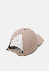 Casquette de baseball beige avec un avant structuré, visière courbée, sangle réglable et doublure intérieure blanche. Présente un petit logo à l'arrière.