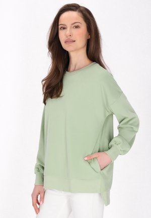Felpa a maniche lunghe verde chiaro con vestibilità comoda, scollo rotondo, polsini a costine e tasche laterali. Tessuto morbido e texture liscia.