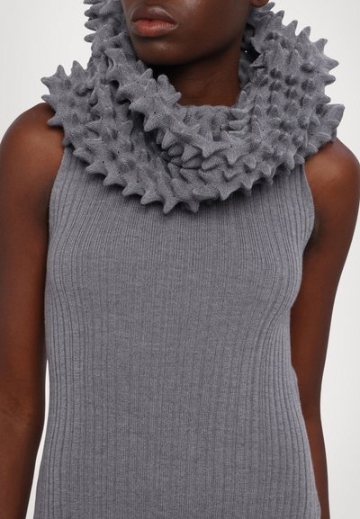 Grau gestrickter Cowl-Neck-Schal mit strukturierten, gewellten Details, kombiniert mit einem ärmellosen, grauen Rippenoberteil. Glatte Textur, einfarbig.