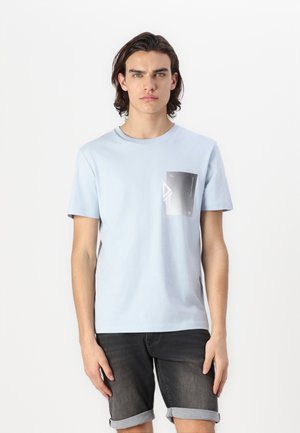 Light blue short-sleeve cotton t-shirt with a front pocket featuring a monochrome graphic design and geometric shapes.