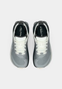 Une paire de chaussures de course sur sentier grises et blanches avec des lacets, vues de dessus sur un fond blanc.