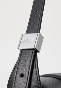 Zwarte lederen tasriem met een zilverkleurige metalen gesp met de gravure "HUGO", met een gestructureerde afwerking en minimalistisch ontwerp.