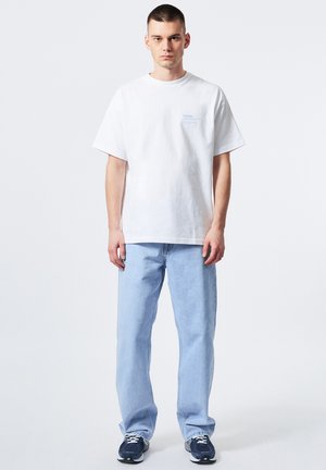 Witte katoenen t-shirt met een relaxte fit, voorzien van een lichtblauwe print. Gecombineerd met lichtblauwe rechte jeans en marineblauwe sneakers.