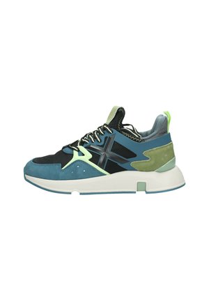 Sneakers con una combinazione di mesh nero e suede teal, con accenti verdi e grigi. Suola bianca chunky, elementi di design geometrico unici.