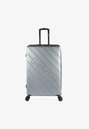 Maleta rígida plateada con estrías diagonales, acentos negros, manija retráctil y cuatro ruedas dobles para mayor movilidad.