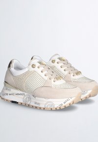 Sneaker beige con una toma superiore testurizzata che presenta mesh e suede. Accenti dorati e suola in gomma con motivo. Lacci e dettagli del logo visibili.
