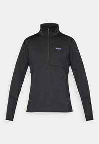 Black pullover made of textured fabric with a half-zip neck, long sleeves, and a patch pocket on the left chest. Features logo detail.