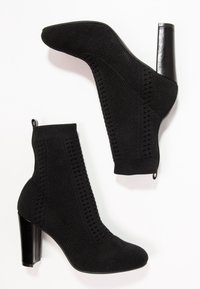 Czarne botki za kostkę z teksturowanym cholewką dzianinową, okrągłym noskiem i masywnym czarnym obcasem. Posiadają pętelkę dla łatwego zakładania oraz wzorzyste detale po bokach.