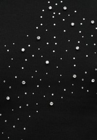 Μαύρο υφασμάτινο ύφασμα με μικρές και μεγάλες διάφανες στρας διασκορπισμένες σε ένα μοτίβο που μοιάζει με αστέρια σε όλη την επιφάνεια.