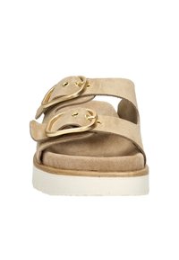 Beige suède sandalen met twee verstelbare banden en goudkleurige gespen. Dikke witte zool met een gestructureerd oppervlak voor grip. Platte uitvoering.