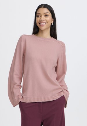 Helles rosa Sweatshirt mit ribbeligem Halsausschnitt und Bündchen, lange Ärmel und lockerer Schnitt. Kombiniert mit burgunderfarbenen Hosen.