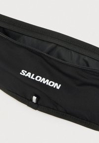 Μαύρη ζώνη τρεξίματος από ανθεκτικό ύφασμα, με φερμουάρ σε τσέπη. Ορατό λευκό λογότυπο "SALOMON". Ομαλή υφή με ελαστικές άκρες.