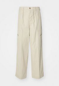 Beige cargo pants with a loose fit, two front pockets, and a slightly textured fabric. Features a button closure and wide-leg design.