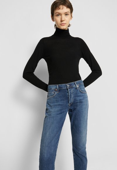 Schwarzes Langarm-Turtleneck-Oberteil, kombiniert mit blauen Jeans, mit entspannter Passform, minimalistischem Design und klassischem Fünf-Taschen-Stil.