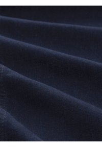 Tejido azul oscuro con una textura suave, que presenta un sutil brillo y pliegues doblados, destacando la suavidad y el flujo del material.