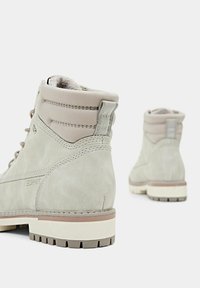Stivaletti alla caviglia in suede grigio con una morbida fodera in pelliccia, upper texturizzato, design con lacci e suola in gomma a contrasto con grip antiscivolo.