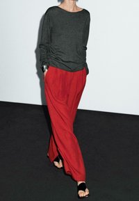 Grå langærmet top med afslappet pasform kombineret med lyserøde, vidde bukser. Outfit'et har bløde teksturer og sorte sandaler.