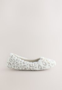 Chausson doux blanc duveteux avec des taches léopard gris clair, un petit nœud à l'avant et une étiquette "Next" près du talon.