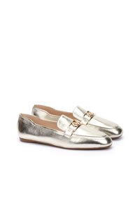 Mocasines metálicos dorados con un acabado de cuero suave, suela plana y un acento decorativo de hardware dorado en la banda a lo largo del empeine.