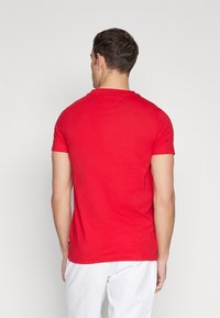 Czerwony t-shirt z okrągłym dekoltem, wykonany z bawełny, krótki rękaw, dopasowany krój, o gładkiej fakturze i bez widocznych wzorów czy akcentów.