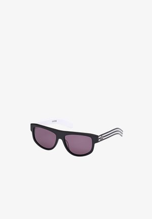 Black plastic sunglasses with purple lenses. Sleek, angular shape with white temples featuring three black stripes. Minimalist design.