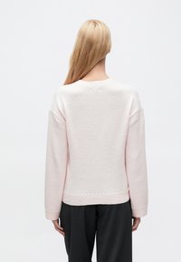 Ανοιχτό ροζ πουλόβερ με υφή, με υπερμεγέθη μανίκια και στρογγυλή λαιμόκοψη. Διαθέτει διακοσμητική ραφή στο τελείωμα.