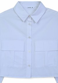 Camicia bianca con colletto e maniche corte, due tasche frontali, chiusura con bottoni e una trama liscia, progettata per una silhouette aderente.