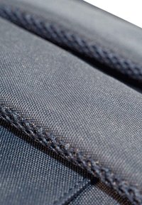 Tessuto blu navy con una trama strutturata, caratterizzato da cuciture visibili lungo i bordi. La vista ravvicinata evidenzia la durata del materiale.