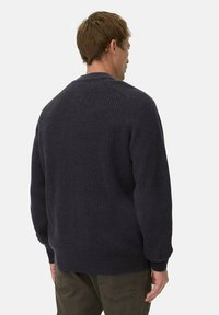 Marineblauer gerippter Pullover mit rundem Ausschnitt, langen Ärmeln und lockerer Passform. Die Textur ist weich und gestrickt mit einem subtilen Muster.