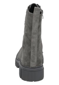 Grijze suede enkellaars met een gestructureerde achterkant, zwarte rubberen zool en ritsluiting. Bevat een logo-detail langs de hak voor branding.