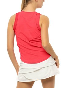 Débardeur de sport rouge sans manches avec un col rond et une texture lisse, associé à une jupe blanche ornée de volants superposés au niveau de l'ourlet.