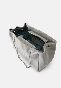 Borsa tote in velluto grigio con manici a catena, dotata di un interno a motivi blu e una tasca con zip. Logo decorativo sulla parte frontale.