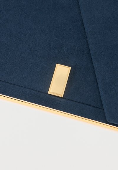 Υφασμα ναυτικό μπλε διπλωμένο με ένα μικρό, ορθογώνιο χρυσό κούμπωμα και χρυσό περίγραμμα κατά μήκος του κάτω άκρου.