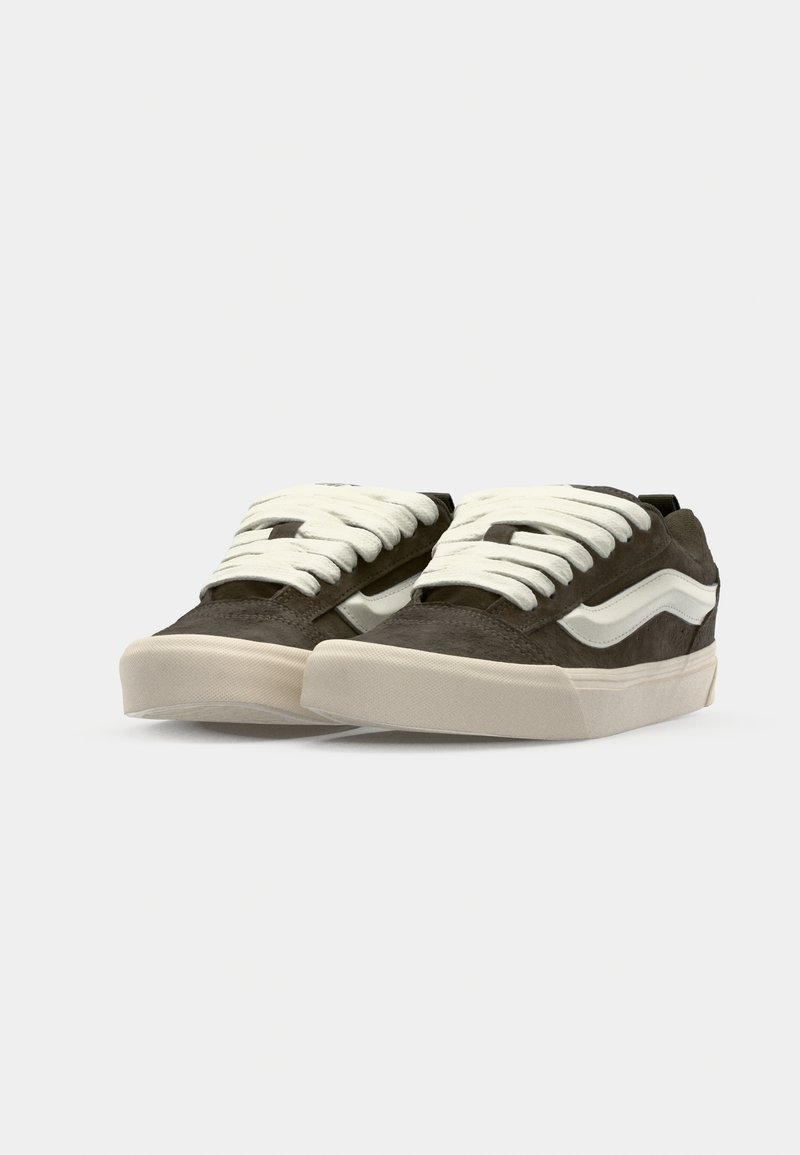 Dunkelgrüne Wildleder-Sneaker mit weißen Schnürsenkeln und einem weißen Seitenstreifen. Sie verfügen über eine strukturierte Gummisohle für besseren Halt und Haltbarkeit.