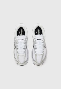 Paire de chaussures de course Nike blanches et argentées avec des lacets blancs, vues de dessus sur un fond clair uni.