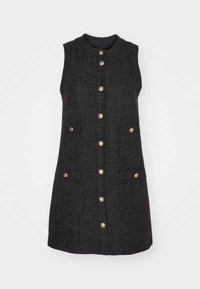 Crna haljina bez rukava od teksturiranog materijala, s prednjim kopčanjem na dugmad, dva prednja džepa i zlatnim detaljima na dugmadima.