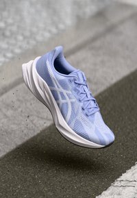 Helles blaues Laufschuhmodell mit einem Obermaterial aus Mesh, strukturiertem Oberflächenmaterial und weißen Akzenten. Verfügt über eine gepolsterte Sohle und flache Schnürsenkel.