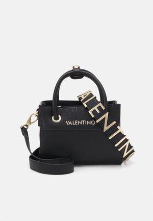 Sac à main en cuir noir texturé avec quincaillerie dorée, doubles poignées et bandoulière amovible, comportant le nom de la marque en relief.