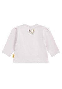 Helle rosa Bluse mit langen Ärmeln und Puffärmeln. Auf der Rückseite befindet sich ein gesticktes Bärenkopf-Design. Weicher Baumwollstoff.