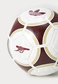 Pallone da calcio bianco e bordeaux realizzato in materiale sintetico, con accenti dorati, motivi geometrici e un logo che rappresenta un cannone.