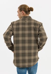 Bruine en beige geruite shirt gemaakt van zacht materiaal, met een relaxte pasvorm, lange mouwen en een ronde zoom. Merklogo op de achterkant van de kraag.