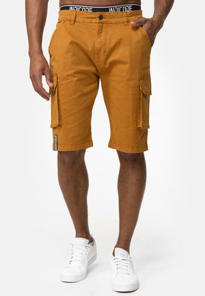 Pantalones cortos cargo en color mostaza, hechos de un tejido duradero, con bolsillos laterales, cierre de botón y una cinturilla con marca.