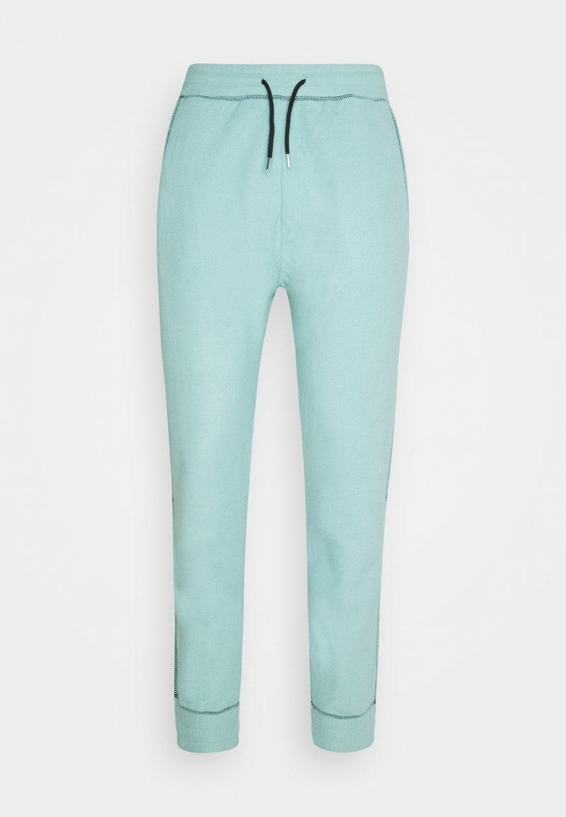 Pantalon de jogging bleu clair avec taille à cordon noire et détails visibles des coutures aux poignets et sur les côtés, présenté sur fond blanc.