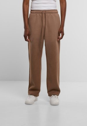 Pantaloni di felpa marroni con vestibilità rilassata, vita elastica e cordino regolabile. Tessuto morbido e gambe dritte. Indossati con sneakers bianche.