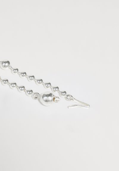 Bracelet en argent avec un motif de perles polies de tailles variées et un fermoir sécurisé, conçu avec une finition métallique lisse.