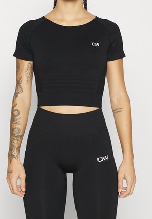 Black cropped athletic top with short sleeves and textured panels, paired with high-waisted black leggings featuring a logo accent.