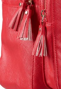 Sac à main texturé rouge avec des accents de franges blanches. Le matériau semble synthétique avec une finition brillante et des détails de couture visibles.