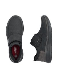 Chaussures décontractées noires avec fermetures auto-agrippantes, dessus texturé, semelle rembourrée et marquage visible "Rieker Antistress" à l’intérieur et sur la bride.