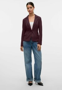 Burgundský blazer s klopovými límci a dvěma předními kapsami, kombinovaný s světle modrými širokými džíny a černými lodičkami se špičatou špičkou.